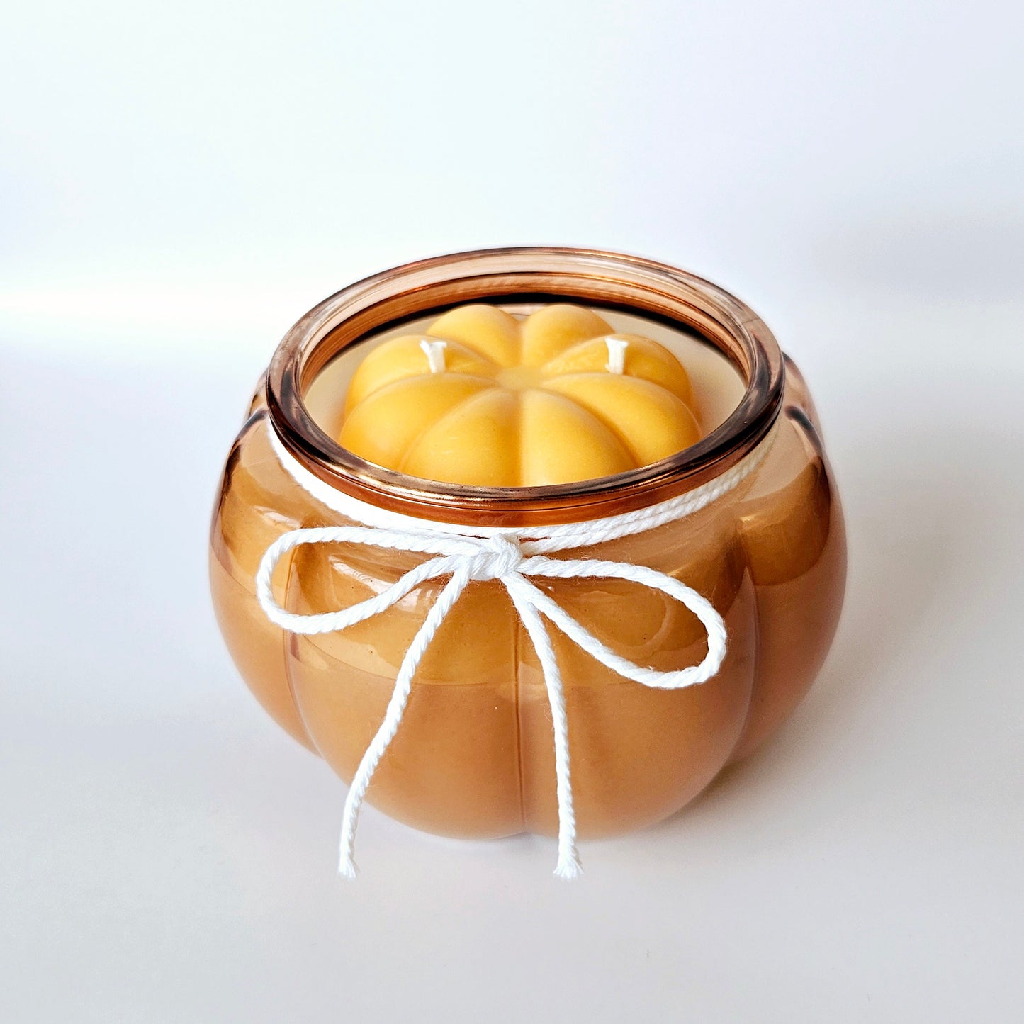 Candle in a glass jar with a decorative bow on a white background