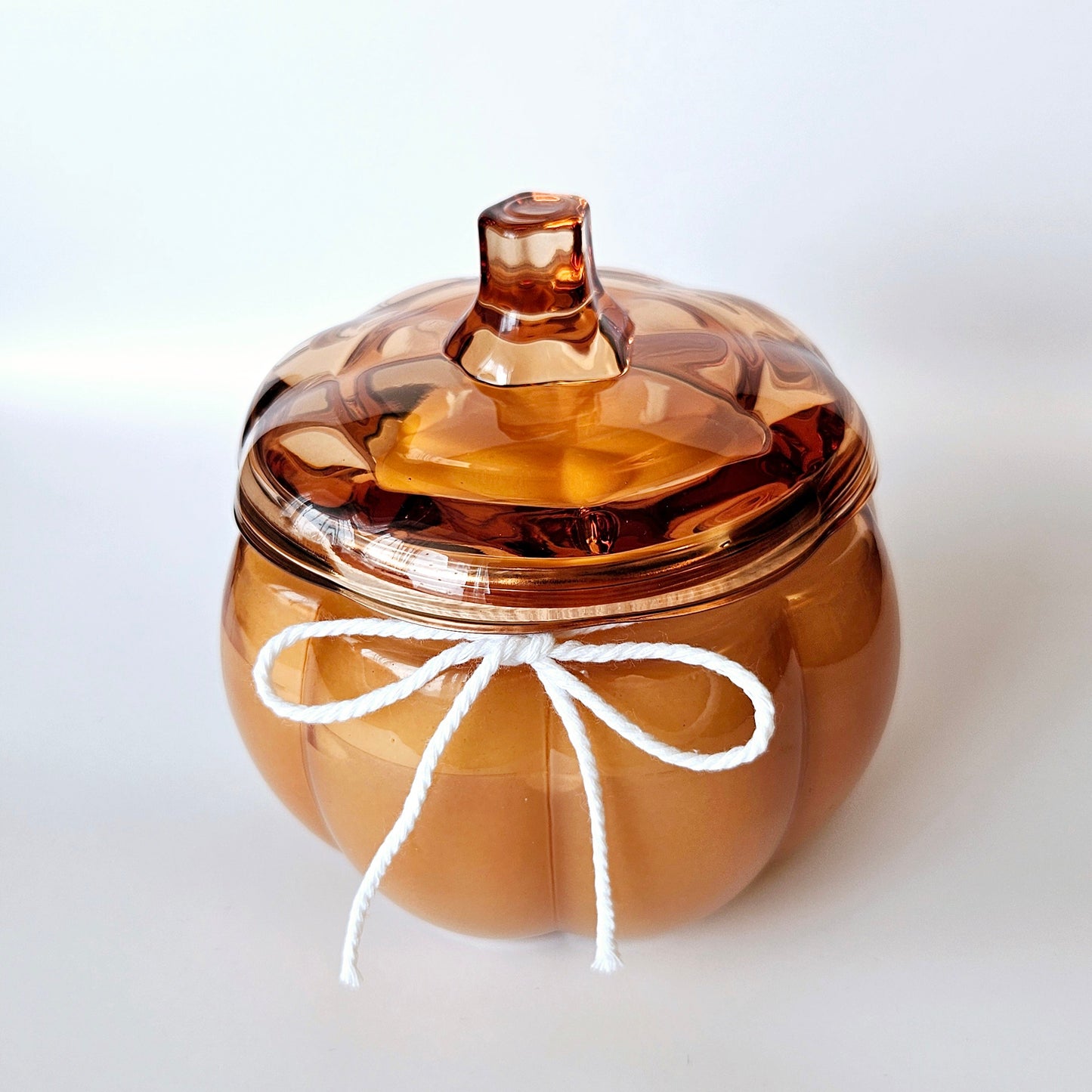 Pumpkin glass jar with a white string bow on a white background